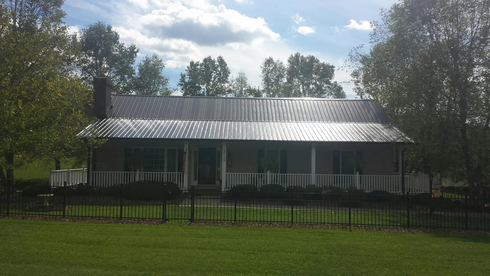 Gray metal roof on a brick ranch with a full width front porch — Gutter Guard Installation work by our crew in Mapleville