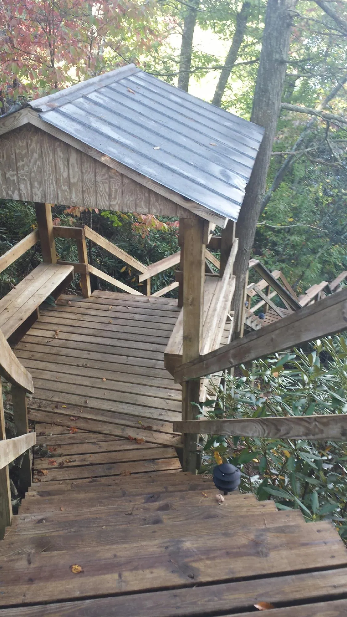 Metal roofed shelter over wooden steps on a wooded walkway — Skylight Repair & Installation work by our crew in Mapleville