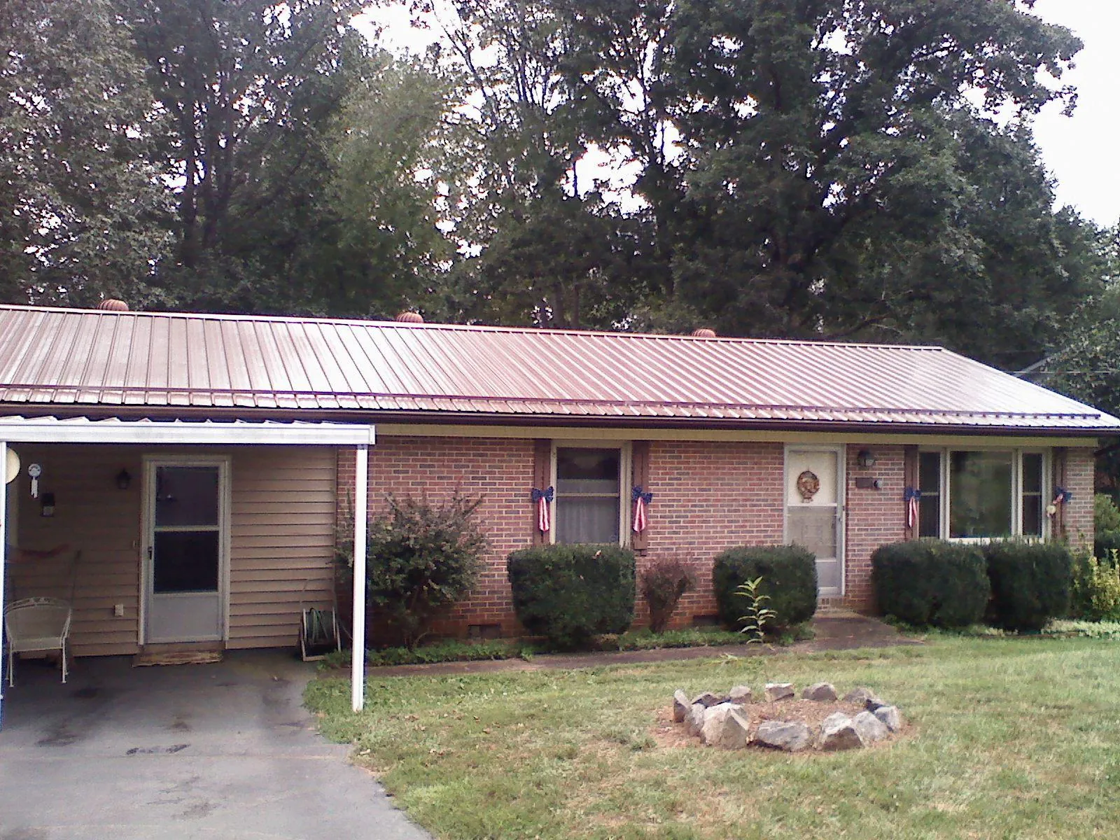 Bronze metal roof and carport on a brick ranch home — Roof Repair work by our crew in Mapleville